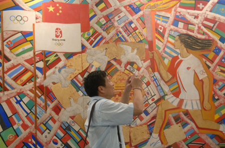 A visitor takes photos of an artwork displayed at the China International Exhibition Center in Beijing, capital of China, Aug. 11, 2008. The Olympic Fine Arts 2008, held by the International Olympic Committee (IOC), opened in Beijing Monday, displaying more than 800 works selected from about 10,000 works of more than 40 countries and regions. [Xinhua]