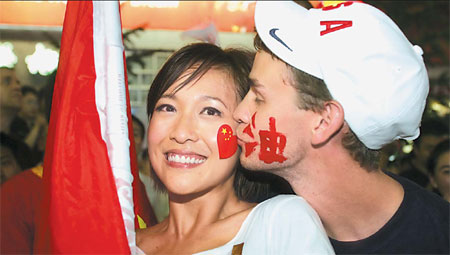 Cross-cultural kiss: These American and Chinese youngsters get into the Olympic mood on opening night at Wangfujing. [China Daily]