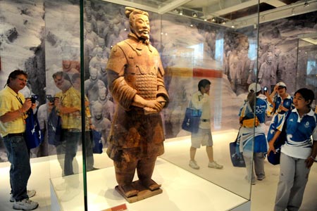 Visitors view a Terracotta Warrior at an exhibiting center in the Olympic Green in Beijing, China, Aug. 11, 2008. Five genuine Terracotta Warriors and Horses, transported from Xi'an, capital of northwest China's Shaanxi Province, are displayed at the center, making it a place for foreign coaches, athletes and tourists to learn Chinese culture. (Xinhua/Li Ziheng)