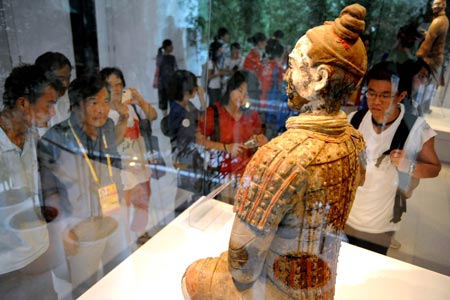 Visitors view a Terracotta Warrior at an exhibiting center in the Olympic Green in Beijing, China, Aug. 11, 2008. Five genuine Terracotta Warriors and Horses, transported from Xi'an, capital of northwest China's Shaanxi Province, are displayed at the center, making it a place for foreign coaches, athletes and tourists to learn Chinese culture. (Xinhua/Li Ziheng)