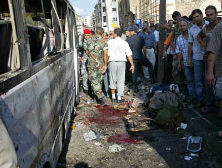 Residents inspect a damaged bus following a bomb blast in the port city of Tripoli in northern Lebanon Aug. 13, 2008. A bomb targeted a bus in the northern Lebanese city of Tripoli on Wednesday. (Xinhua/Reuters Photo)
