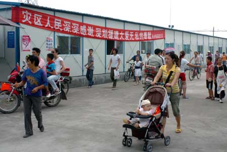  People walk along prefabs in Shifang City of southwest China's quake-hit Sichuan Province August 12, 2008. The Sichuan Provincial Government announced on Tuesday that the 10 million people or 4.45 million households, whose homes were destroyed by the May 12 earthquake, had all moved into makeshift houses by last Wednesday. (Xinhua/Yuan Jian) 
