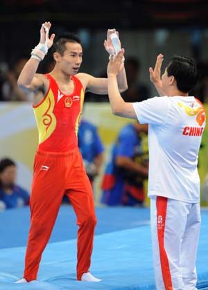 China's Xiao Qin (L) celebrates with his coach after the horizontal bar competition during gymnastics artistic men's team final of the Beijing 2008 Olympic Games at National Indoor Stadium in Beijing, China, Aug. 12, 2008. The Chinese team claimed the title of the event with 286.125 points. (Xinhua/Cheng Min)