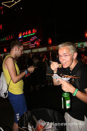 A foreign tourist eats a snack at the Donghuamen food street in Beijing, August 13, 2008. [Asianewsphoto] 