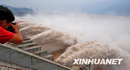 A photographer snaps photos of the water gushing from the giant sluice gates of the Three Gorges Dam on the Yangtze River on Wednesday, August 13, 2008. This is the largest volume of water released through Three Gorges Dam to lower water levels since the start of the flood season. The release has caused water levels in the middle and lower reaches of the Yangtze River to rise. [Photo: Xinhua] 