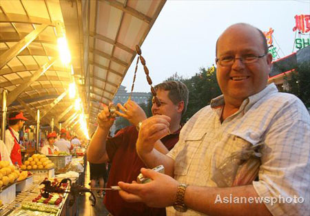 A foreign tourist shows the snack he bought at the Donghuamen food street in Beijing, August 13, 2008. [Asianewsphoto]