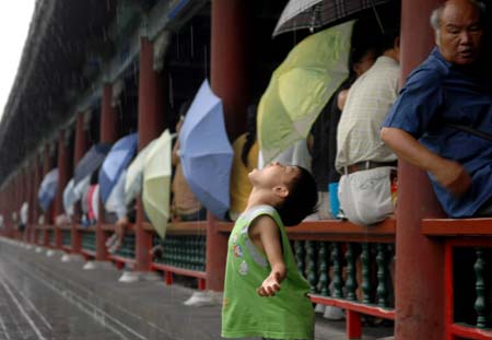 A child plays in the rain outside a corridor at the Temple of Heaven in Beijing, captial of China, Aug. 14, 2008. Beijing witnessed a heavy rainfall Thursday afternoon. 