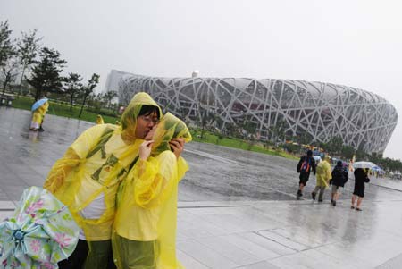 A couple kiss outside the National Stadium, also known as 'Bird's Nest' in Beijing, capital of China, Aug. 14, 2008. A heavy rainfall Thursday afternoon did not stopped people from visiting the stadium.
