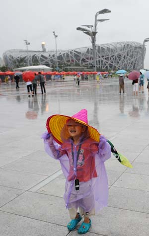 A child plays in the rain at the National Stadium, also known as 'Bird's Nest' in Beijing, capital of China, Aug. 14, 2008. A heavy rainfall Thursday afternoon did not stopped people from visiting the stadium.