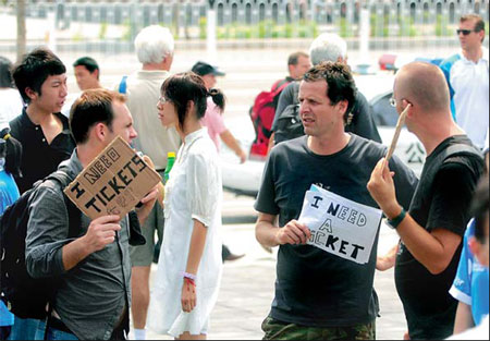 Foreigners outside Beitucheng subway station on Wednesday hold up signs advertising they are in the market for Olympic tickets. 