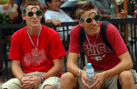 Two foreign tourists wearing sunglasses shaped into the logo of the Olympic Games rest at Wangfujing Street in Beijing on August 13, 2008. More and more foreign tourists visit Beijing as the Beijing Olympics are going on here.