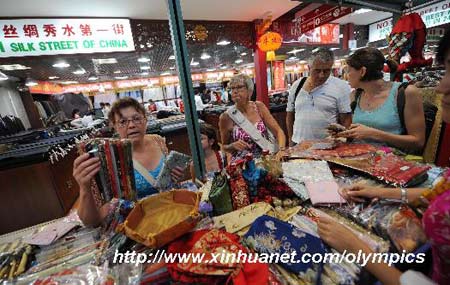 Foreigners select silk handicrafts at a store in Xiushui Market (Silk Street market), a popular tourist market, in Beijing on August 13, 2008. 