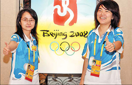 Jin Dongri (right) and Zheng Weiwei, a Chinese master student at a French university, stand in front of an Olympic billboard.