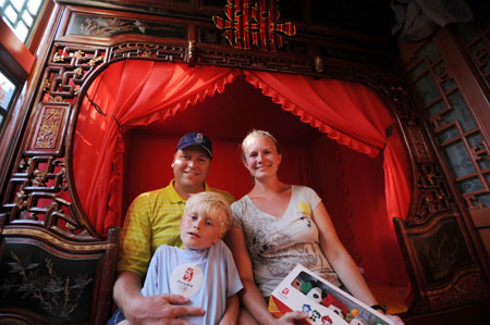 Australian visitors sitting on a traditional Chinese bridal bed pose for a photo in Beijing August 15, 2008. A Beijing household, at Nanguanfang Hutong near Shichahai Lake, a tourist attraction in downtown Beijing, is one of about 600 homestay families chosen for foreign visitors during the Beijing Olympic Games. [Xinhua]
