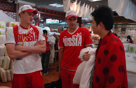 Two Russian athletes bargain with a shopkeeper in Xiushui Market (Silk Street market), a popular tourist market in Beijing