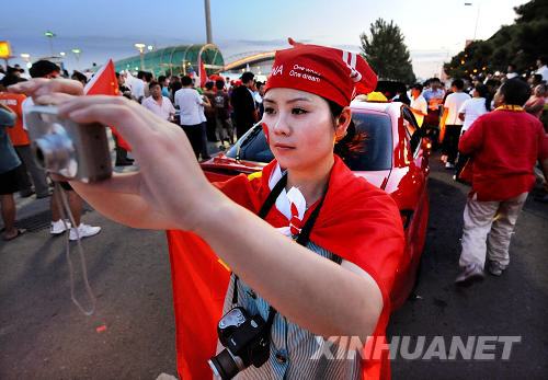 A Chinese fan dressed up for the women's soccer quarter-final match between China and Japan on August 15. In the background, fans stream into the Qinghuangdao Olympic Sports Center. [Li Ziheng/Xinhua]