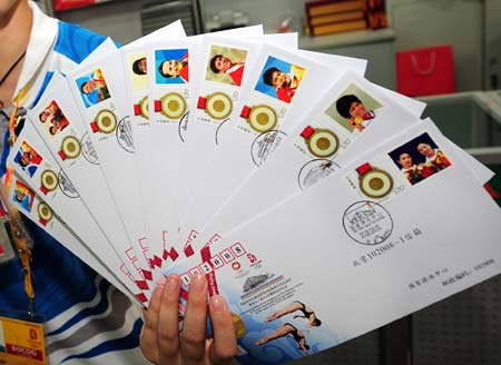 A volunteer shows the commemorative envelopes marking the gold medalists of China during the 29th Olympic Games, in Beijing, China, Aug. 19, 2008. These commemorative envelopes, each bearing a photo of the athlete who won gold medal for China during the Beijing Olympics, started to be sold to the public here on Tuesday. [Li Ziheng/Xinhua]
