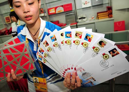 A volunteer shows the commemorative envelopes marking the gold medalists of China during the 29th Olympic Games, in Beijing, China, Aug. 19, 2008. These commemorative envelopes, each bearing a photo of the athlete who won gold medal for China during the Beijing Olympics, started to be sold to the public here on Tuesday. [Li Ziheng/Xinhua]