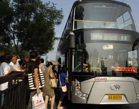 People get on a double decker bus at a bus stop in Beijing, capital of China, Aug. 19, 2008. Statistics shows that the public traffic sector has registered a passenger transport volume of 20 million persons per day since the control of vehicle use in Beijing last month. [Zhang Shanchen/Xinhua]