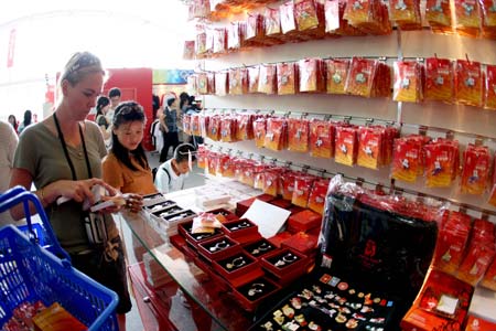 Tourists select the Olympic-related souvenirs at an exclusive shop selling the licensed products of the Beijing 2008 Olympic Games in the Olympic Green in Beijing, capital of China, Aug. 19, 2008. The Olympic-related souvenirs in the shop are sold well as the event is drawing to an end.[Wang Wen/Xinhua]
