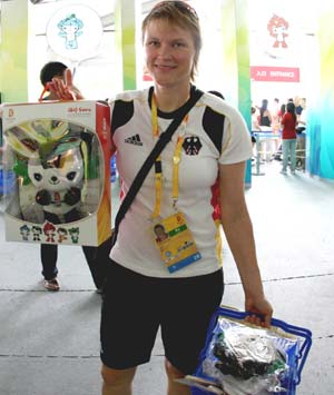 A tourist shows a doll of 'Fuwa', mascot of the Beijing Olympic Games, after buying a lot of souvenirs at an exclusive shop selling the licensed products of the Beijing 2008 Olympic Games in the Olympic Green in Beijing, capital of China, Aug. 19, 2008. The Olympic-related souvenirs in the shop are sold well as the event is drawing to an end.[Wang Wen/Xinhua]