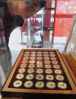 A man looks at commemorative coins of 'fuwa', mascots of Beijing Olympic Games in a shop in Taiyuan, capital of north China's Shanxi Province, Aug. 12, 2008. The Olympic souvenirs sell briskly in Taiyuan as the event goes on.[Xinhua]