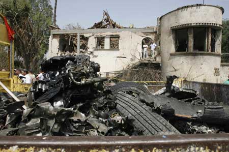 A truck transporting the wreckage of a car moves past a damaged house at the site of a suicide bomb attack in Issers, 55 km (34 miles) east of Algiers, August 19, 2008. A bomb attack east of Algiers killed 43 people and wounded 45 on Tuesday. (Xinhua/Reuters Photo)