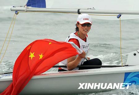Xu Lijia of China celebrates with Chinese national flag after clinched the bronze medal in the laser radial medal race of the Beijing Olympic Games sailing event in Olympic co-host city Qingdao, east China's Shandong Province, Aug. 19, 2008.[Xinhua]