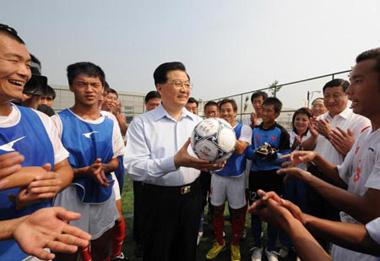 Chinese President Hu Jintao holds a football after writing 'striving to become strong and fighting for the best' on it at the training center for Paralympic athletes in Beijing. [Xinhua]