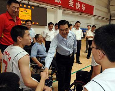 Chinese President Hu Jintao shakes hands with wheelchair basketball players at the training center for Paralympic athletes in Beijing. [Xinhua]