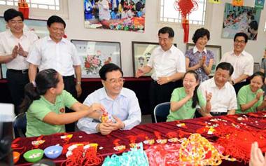 Chinese President Hu Jintao joins some disabled people who are learning to make handicrafts in Shichahai community home for the disabled in Beijing. [Xinhua]