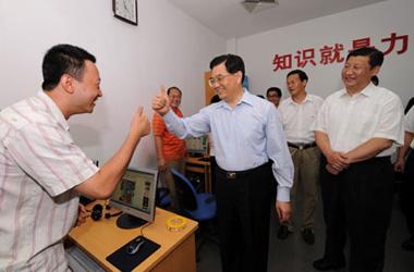 Chinese President Hu Jintao communicates with a disabled man who is surfing on the Internet in Shichahai community home for the disabled in Beijing. [Xinhua]