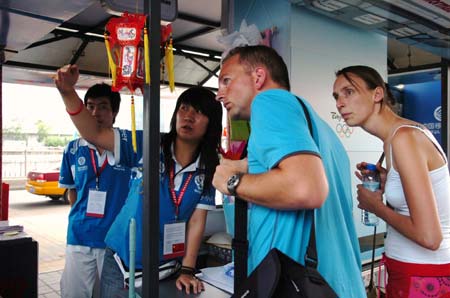 A volunteer guides the road for foreign visitors at a volunteer service station of the Beijing Exhibition Center in Beijing, capital of China, Aug. 20, 2008. Many volunteers appear at public places during the Beijing 2008 Olympic Games in Beijing and Olympics co-host cities to provide information, emergency aid and translation services etc. for people from around the world. (Xinhua/Zhao Yusi)
