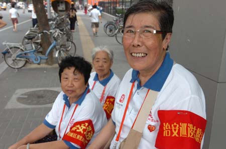 Volunteers who help maintain social order in the communities pose for photos at Yushuguan Community of the Exhibition Road in Beijing, capital of China, Aug. 20, 2008. Many volunteers appear at public places during the Beijing 2008 Olympic Games in Beijing and Olympics co-host cities to provide information, emergency aid and translation services etc. for people from around the world. (Xinhua/Zhao Yusi) 