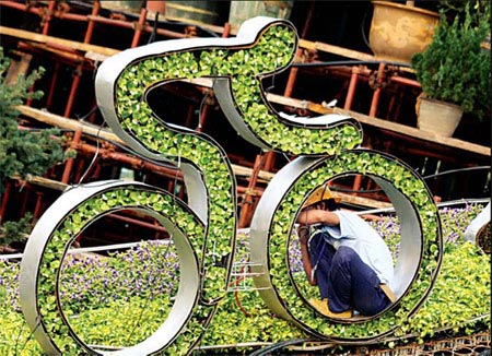 A worker fixes a 'green' cyclist at Tian'anmen Square to celebrate the Olympic Games. [China Daily] 