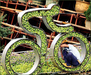 A worker fixes a 'green' cyclist at Tian'anmen Square to celebrate the Olympic Games. [China Daily]