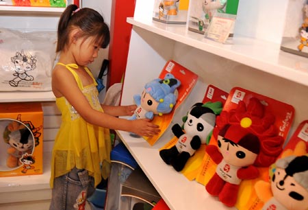 A girl looks at Fuwa, mascots of the Beijing Olympic Games, in a shop in Taiyuan, capital of northern China's Shanxi Province on August 12, 2008. The Olympic souvenirs sell briskly in Taiyuan as the event goes on. [Photo: Xinhua]