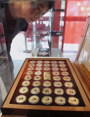A man looks at commemorative coins of 'fuwa', mascots of Beijing Olympic Games in a shop in Taiyuan, capital of north China's Shanxi Province, Aug. 12, 2008. The Olympic souvenirs sell briskly in Taiyuan as the event goes on. [Peng Yang/Xinhua]