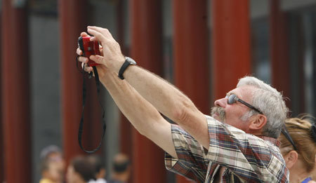 A foreign tourist takes photos on the Qianmen Street in Beijing, capital of China, Aug. 20, 2008. [Lu Jinbo/Xinhua]