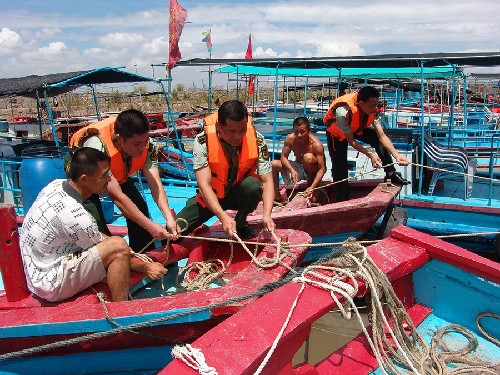 Police officers in Shantou coastal areas in Guangdong aid local fishermen fix their hawser on August 21, 2008. Typhoon Nuri, the 12th tropical storm this year, was forecast to land on South China's Guangdong Province Friday. [Photo: Xinhua]