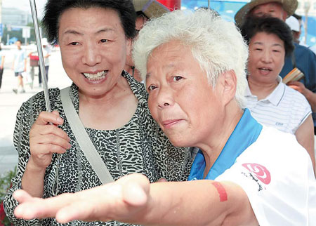 Wang Zhifu gives directions yesterday to a woman tourist at Xidan Cultural Square. Huo Yan