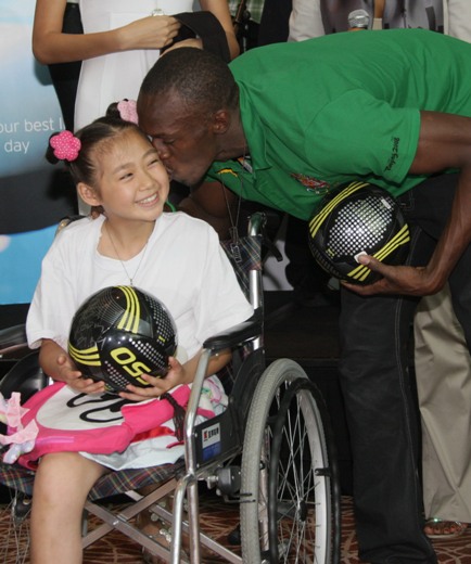 Jamaican Usain &apos;Lightening&apos; Bolt kisses Huang Siyu (left) from the earthquake stricken Ying Xiu Town, Sichuan Province. The winner of 3 Olympic gold donates 5 million USD through China Redcros on August 23. He wishes the children in the disaster affected region to retain their smile and he also invites 6 children from the region to his hometown Jamaica for a tour. [china.org.cn]