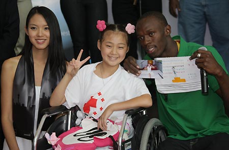 Jamaican athlete Usain Bolt (R) poses for photos with Huang Siyu (C), a girl from the earthquake-hit Yingxiu Town of southwest China's Sichuan Province, during a donation ceremony in Beijing, capital of China, Aug. 23, 2008. Usain Bolt, who won three gold medals in the men's 100m, men's 200m, and men's 4x100m relay competitions of the Beijing 2008 Olympic Games, donates US$50,000 through the Chinese Red Cross Foundation (CRCF) to the children in the earthquake-hit areas of China on Saturday, and invites six earthquake-affected children to travel to Jamaica. [Xinhua]