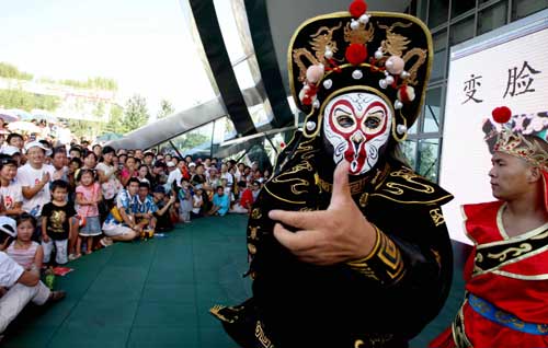 An Sichuan opera actor performs 'face-changing' stunt around the Olympic Green north of Beijing on August 22, 2008. Performances brought by artists home and abroad have been staged in the Olympic Green during the Beijing Games. [Xinhua]