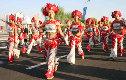 Performers wave to visitors during a parade along the Olympic Green in Beijing, August 22 2008. Performances brought by artists home and abroad have been staged in the Olympic Green during the Beijing Games.