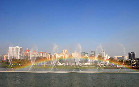 A rainbow rises along side fountains against the clear sky in Beijing Olympic Park Friday. [Xinhua]  