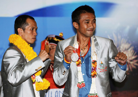 Somjit Jongjohor of Thailand (L), who won the gold medal of the Men's Fly (51kg) of the 2008 Beijing Olympic Games boxing event, and Manus Boonjumnong of Thailand, who won the silver medal of the Men's Light Welter (64kg) bout of the 2008 Beijing Olympic Games boxing event, gesture to people upon their arrival at the Bangkok International Airport in Bangkok, capital of Thailand, Aug. 25, 2008. The Thailand delegation claimed 2 golds and 2 silvers, ranking 31st at the gold medal standings of the Beijing Olympics. (Xinhua/Ling Shuo) 