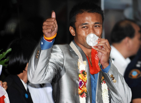 Manus Boonjumnong of Thailand, who won the silver medal of the Men's Light Welter (64kg) bout of the 2008 Beijing Olympic Games boxing event, gestures to people upon his arrival at the Bangkok International Airport in Bangkok, capital of Thailand, Aug. 25, 2008.
