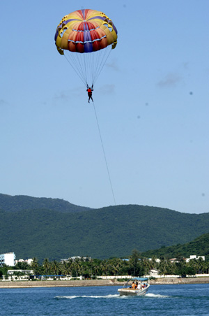 Tourists play parasailing near the Dadonghai Beach in Sanya City, south China&apos;s Hainan Province, Aug. 25, 2008. Beautiful scenery and agreeable weather in the island province is attracting increasingly more tourists after the Beijing Olympic Games. (Xinhua Photo/Zhao Yingquan)