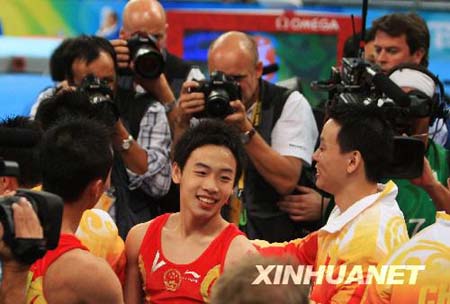 Zou Kai (R) of China claps hands with a coach after his performance of floor exercises during gymnastics artistic men's team final of the Beijing 2008 Olympic Games at National Indoor Stadium in Beijing, China, Aug. 12, 2008. 